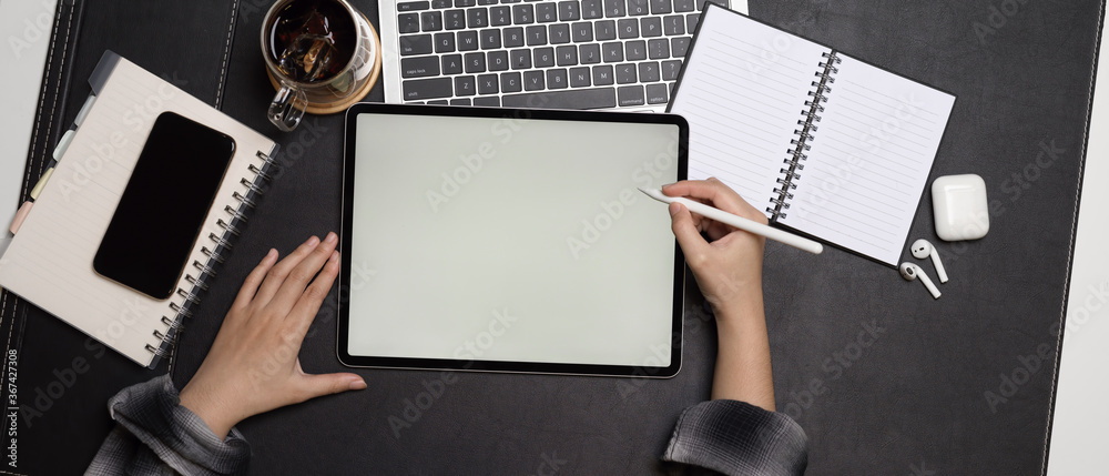 Obraz premium Female using mock up tablet with stylus pen on dark office desk