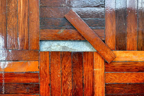 A piece of parquet floor tile comes unglued and loose due to wear and tear. photo