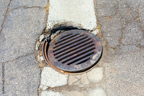 Obraz na plátně Round storm drain grate over damaged manhole on the road