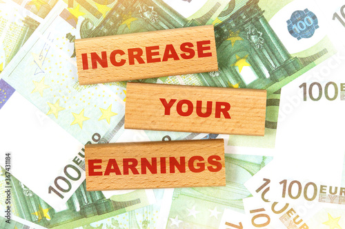 Against the background of euro bills, the text is written on wooden blocks - INCREASE YOUR EARNINGS