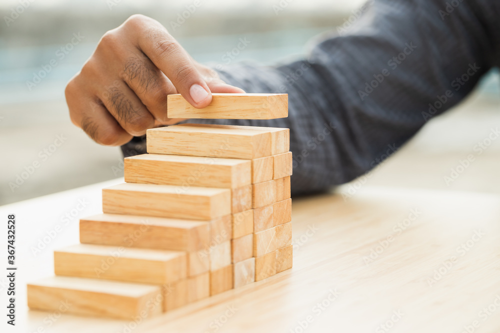 Close up male hand holding arranging or pick up the block wood game and stacking. Growth of Business financial investment and bankrupt concept. Close up male hand holding arranging or pick up the block wood game and stacking. Growth of Business financial investment and bankrupt concept.