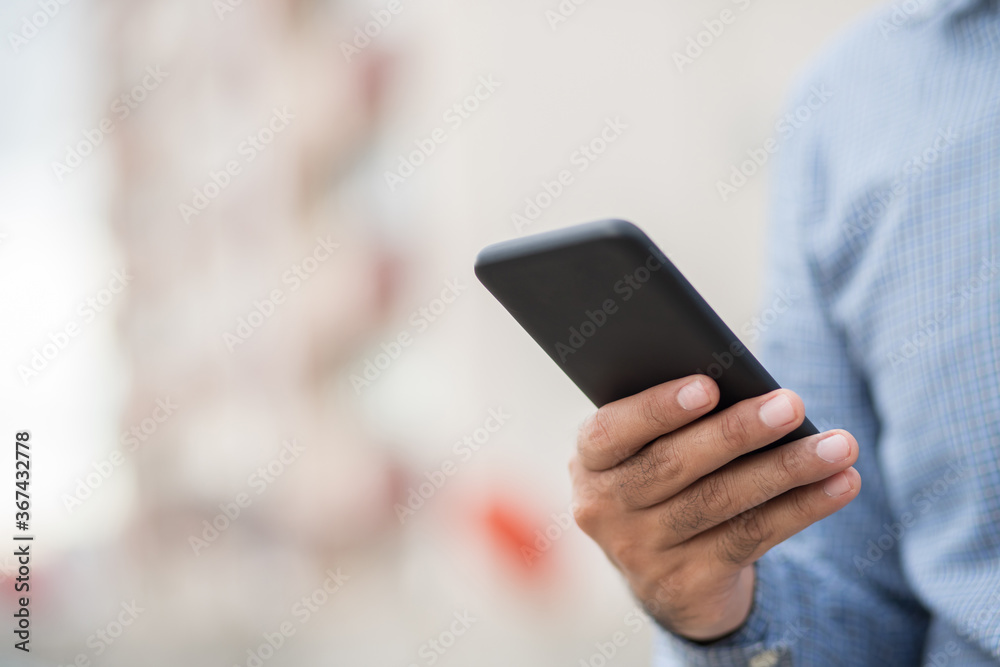 Close up male hands holding using black smartphone on city background. Close up male hands holding using black smartphone on city background.