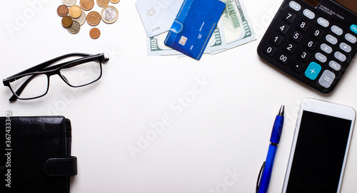 Wallet, credit card, money, glasses, blue pen, telephone and calculator lie on a light background. Business concept. Workplace close up photo