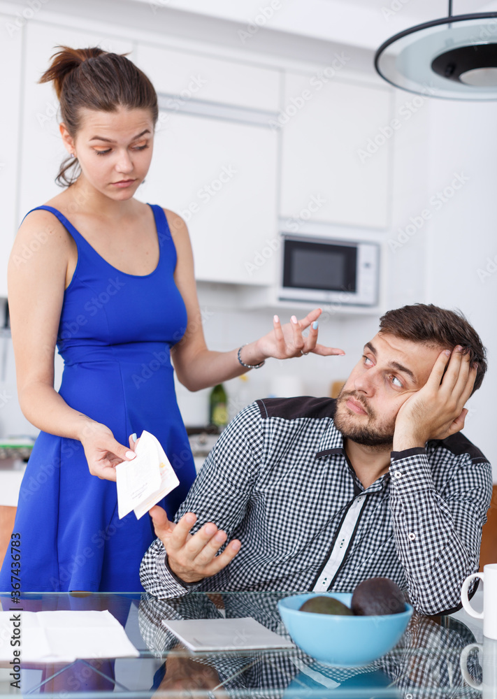 Φωτογραφία Unhappy young woman and man with financial bills having conflict at home