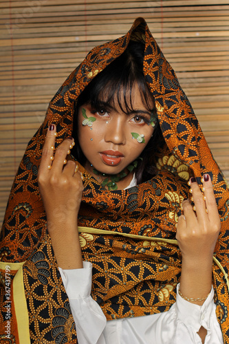 Beautiful Young Woman and Flowers in Her Face with Jarik as a head covering. Pretty woman with brown skin photo