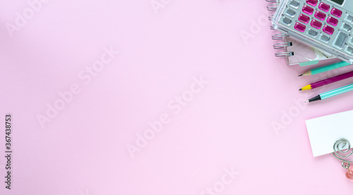 Various colorful stationery for school and office on pink background with copyspace