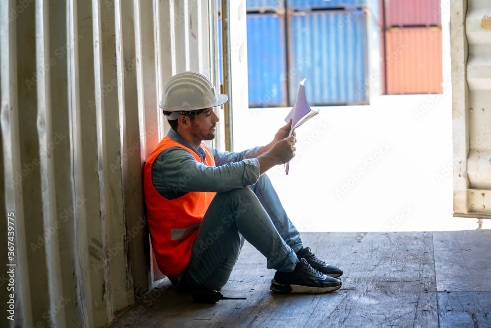 Container worker sitting failed and stressed at cargo container,Work crisis. Container worker sitting failed and stressed at cargo container,Work crisis.