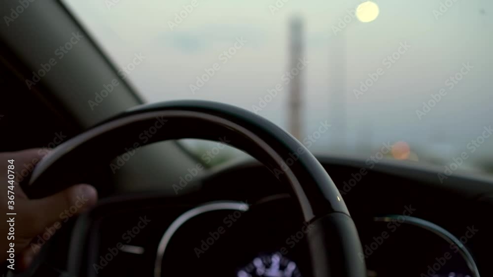 male hands on the steering wheel, a man drives a car at dusk