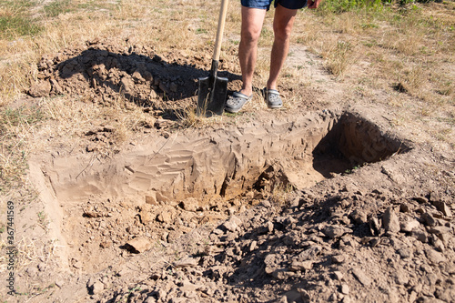 man digs a hole for a coffin in a cemetery
