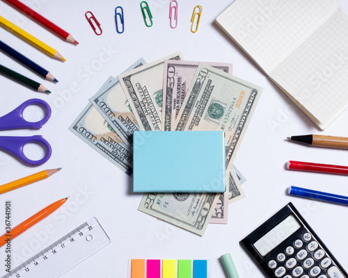 Top view photo of dollars for shopping in the center and colorful stationery, isolated on white with copy space