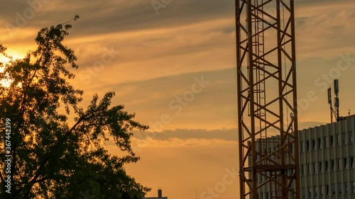 Timelapse of the undergoing sun in orange shades of colors with the part of a crane and a building as foreground elements photo