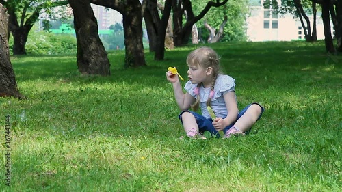 Beautiful little girl blowing soap bubbles in the garden