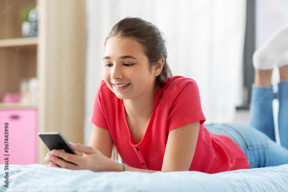 children, technology and communication concept - smiling teenage girl texting on smartphone at home children, technology and communication concept - smiling teenage girl texting on smartphone at home