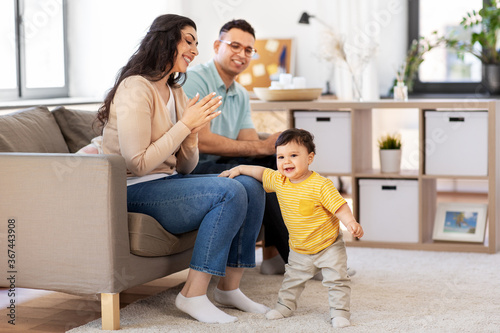 family and people concept - happy mother, father and baby son sitting on sofa at home