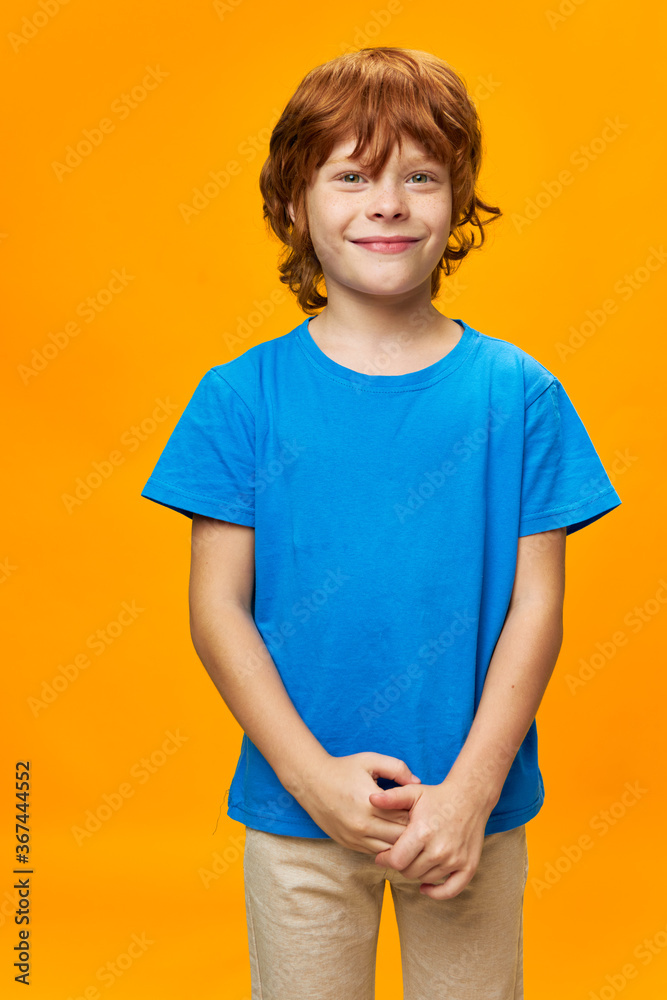 Happy boy cropped view blue t-shirt yellow background red hair