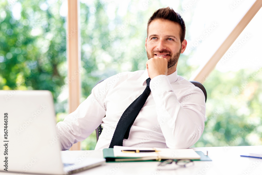Cropped shot of businessman looking at camera and smiling while sitting at office desk Cropped shot of businessman looking at camera and smiling while sitting at office desk