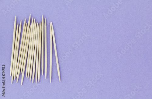 Wooden toothpicks on purple paper background. Copy space for text.