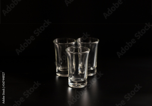 Empty shot glasses for alcohol cocktail on black background.