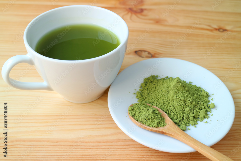 Cup of Hot Matcha Green Tea with a Plate of Matcha Tea Powder on Wooden Table Cup of Hot Matcha Green Tea with a Plate of Matcha Tea Powder on Wooden Table