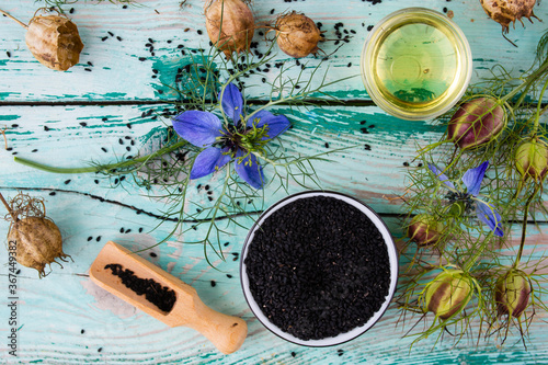Black cumin flowers and seeds on a wooden background. Healthy diet and alternative medicine.