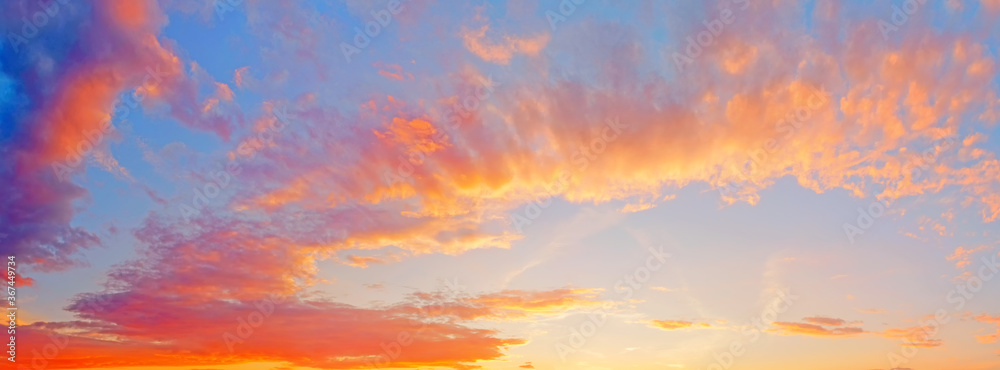 summer sunset sky landscape panorama background with sun below horizon. Ultra wide view of clouds skyline on evening. Natural blue red yellow orange color of cloudscape