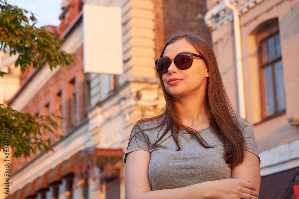 Beautiful woman in sunglasses stands in the urban environment