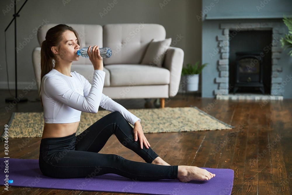 Young woman resting after exercise at home in a living room. Young woman resting after exercise at home in a living room.
