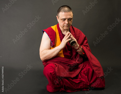 Tibetan Buddhist monk teacher in a burgundy yellow outfit suit