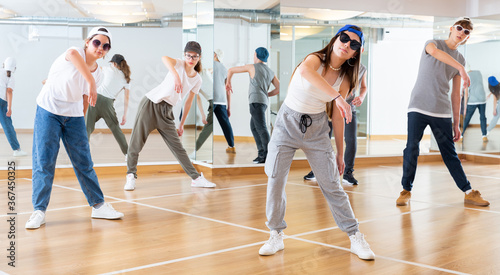 Positive teenage girls and boys training hip hop in dance studio, dance classes for teens