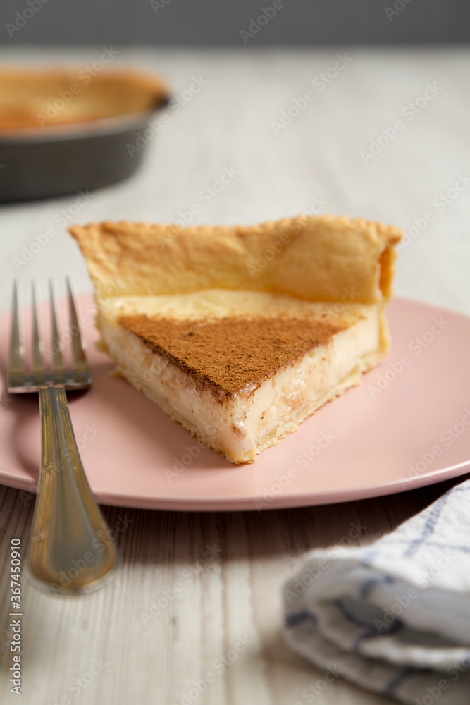 Homemade Sugar Cream Pie on a pink plate on a white wooden background, side view. Close-up.