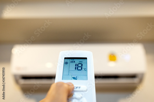 фотографія People hold a remote control with air conditioner,hand turn on the air condition