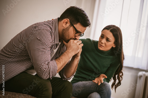 Fototapeta Man is sad and depressed, his wife is consoling him.