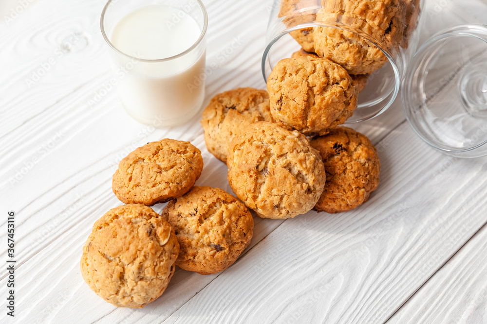 Homemade oatmeal cookies on white wooden table with milk on background Homemade oatmeal cookies on white wooden table with milk on background