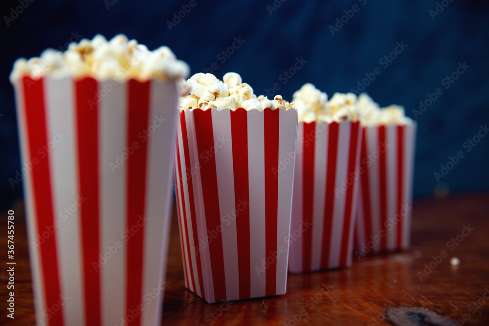 Popcorn in striped retro red and white cardboard box for cinema on wooden table Popcorn in striped retro red and white cardboard box for cinema on wooden table