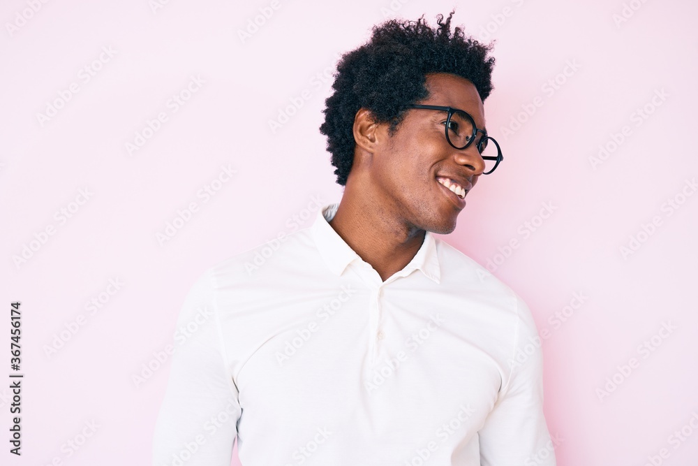 Handsome african american man with afro hair wearing business shirt and glasses looking to side, relax profile pose with natural face and confident smile. Handsome african american man with afro hair wearing business shirt and glasses looking to side, relax profile pose with natural face and confident smile.
