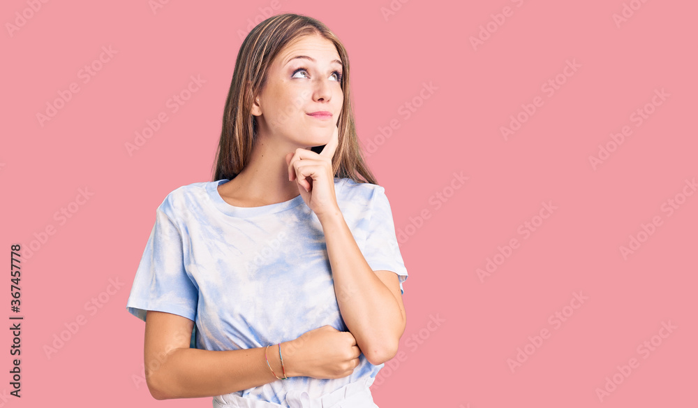 Young beautiful blonde woman wearing tye die tshirt serious face thinking about question with hand on chin, thoughtful about confusing idea Young beautiful blonde woman wearing tye die tshirt serious face thinking about question with hand on chin, thoughtful about confusing idea