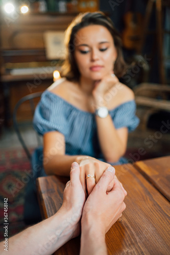 male hands holding female hand with wedding ring on finger.