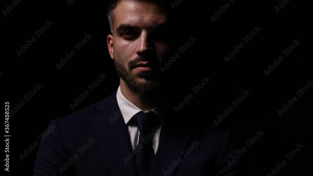mysterious elegant businessman in suit smiling, moving head and fixing suit, holding hand to face and touching chin and lips, grabbing throat and posing in a fashion light on dark background mysterious elegant businessman in suit smiling, moving head and fixing suit, holding hand to face and touching chin and lips, grabbing throat and posing in a fashion light on dark background