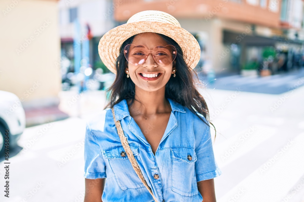 Young beautiful indian woman wearing heart sunglasses smiling happy at the city.