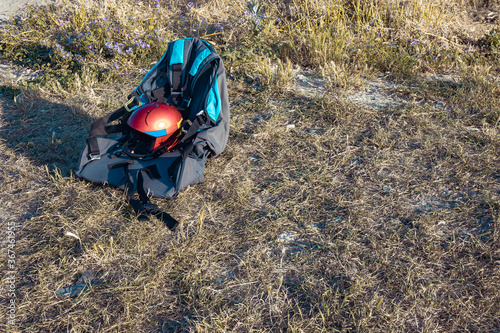 Equipment for the paraglider lies on the ground and awaits flight. Helmet and paraglider chair close-up.