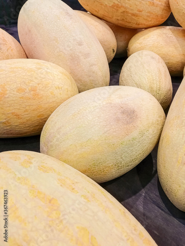 Ripe yellow melons torpedo lie on the counter of the store.