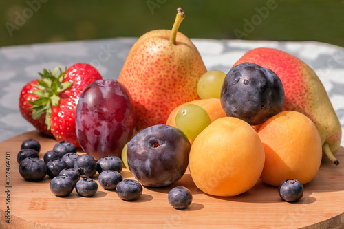 An assortment of fresh and ripe fruits and berries on a wooden kitchen board.
