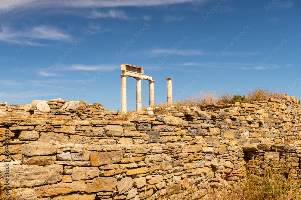 Antique doric columns and ruins on DELOS Island - mythological, historical, and archaeological site in Greece during sunny day with a blue sky.