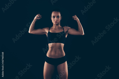 Portrait of her she nice-looking attractive powerful content sportive strong enduring lady demonstrating muscles isolated over black background