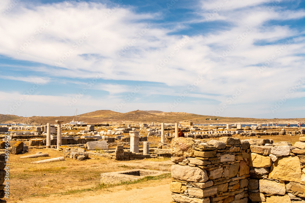 Landscape of Delos Island in Greece - view from the hill on the island with blue cloudy sky and big area of ancient ruins.