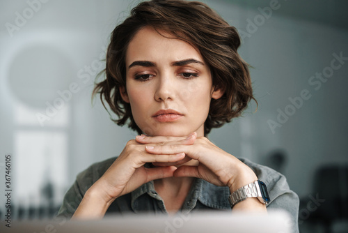 Принти на полотні Image of young brooding woman working with laptop while sitting at table