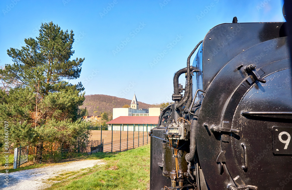 Steam locomotive drives past a sports field with a church tower in the background. Dynamic due to motion blur. Steam locomotive drives past a sports field with a church tower in the background. Dynamic due to motion blur.