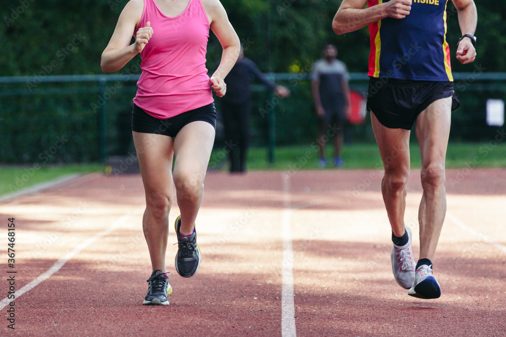 Active sporty woman and man in sportswear running. Selective focus on the them and defocused background.