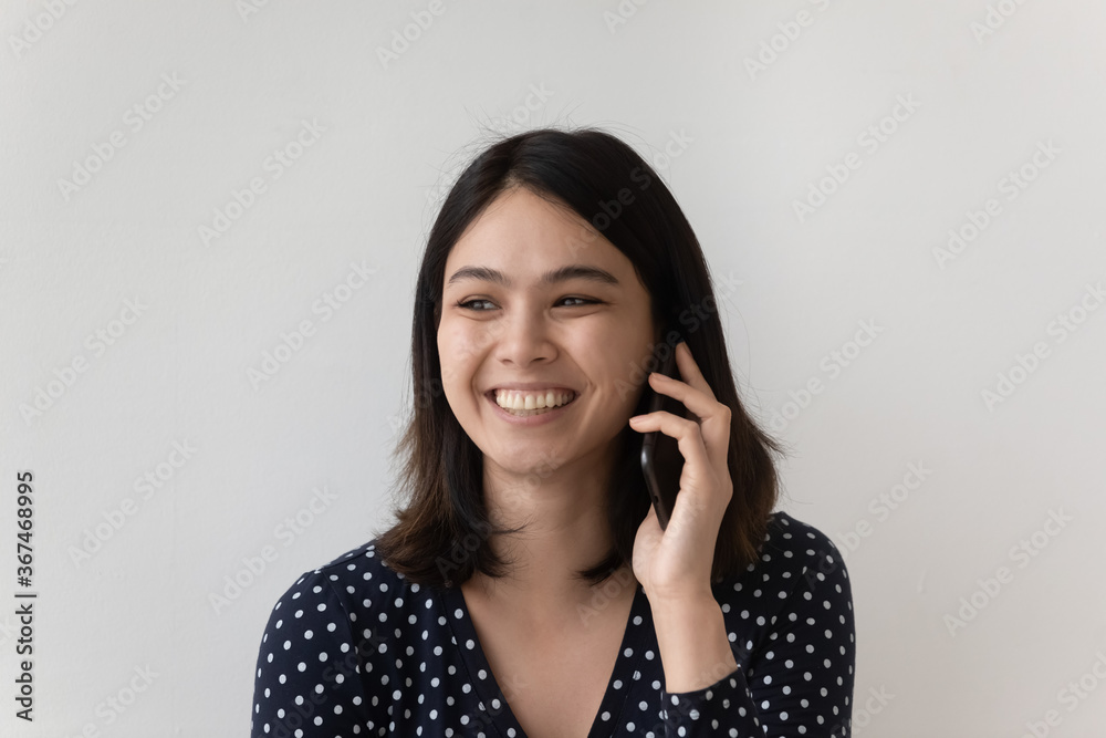 Close up of happy Vietnamese girl isolated on grey studio background engaged in pleasant cellphone call talk, smiling young Asian woman have fun laugh speak on smartphone gadget technology concept Close up of happy Vietnamese girl isolated on grey studio background engaged in pleasant cellphone call talk, smiling young Asian woman have fun laugh speak on smartphone gadget technology concept