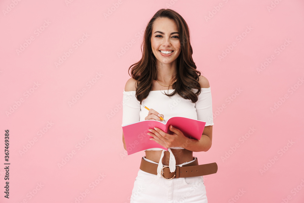 Image of smiling young woman writing in exercise book and smiling Image of smiling young woman writing in exercise book and smiling